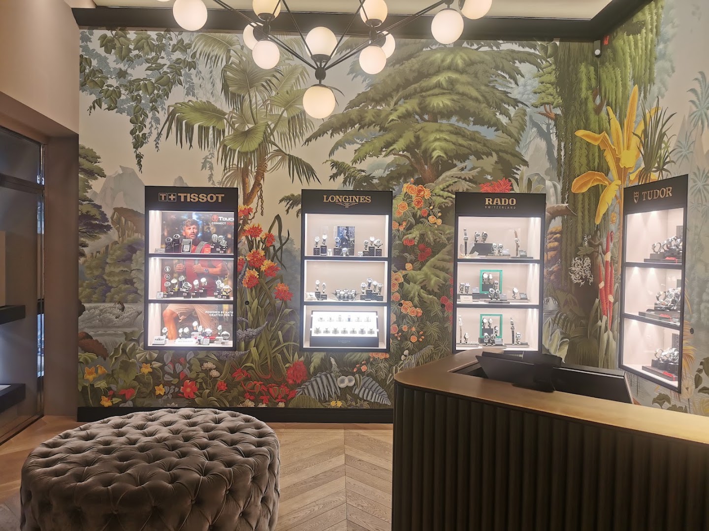 Innenraum von KURZ 1948 in Luzern mit botanischem Wandbild und beleuchteten Uhren-Vitrinen von Tissot, Longines, Rado und Tudor